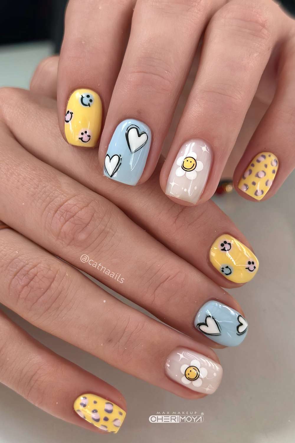 Blue and yellow nails with hearts and smiley faces
