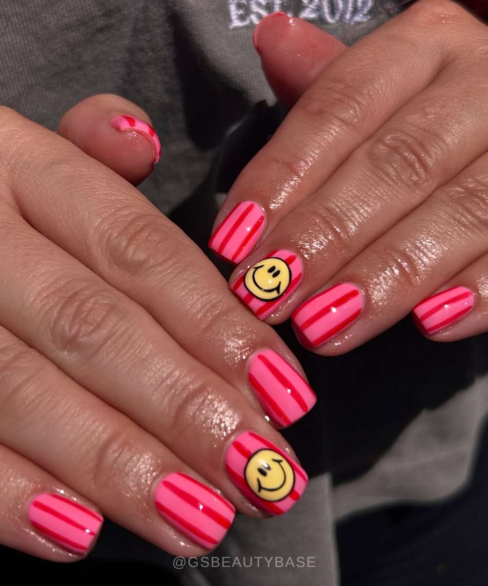 Pink striped nails with happy face motif