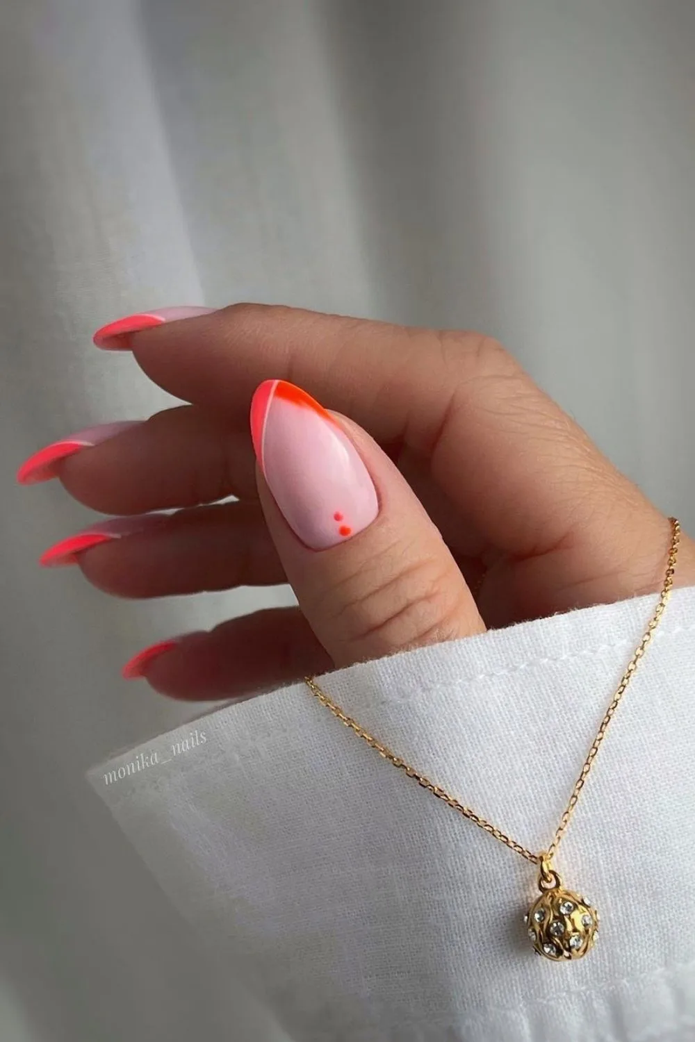 orange manicure with necklace around finger