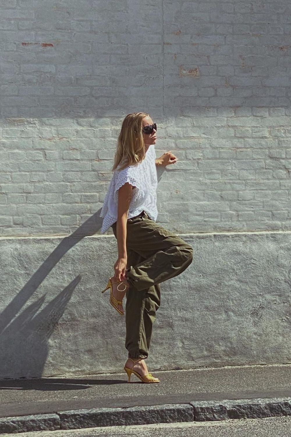 woman in white lace shirt and green trousers