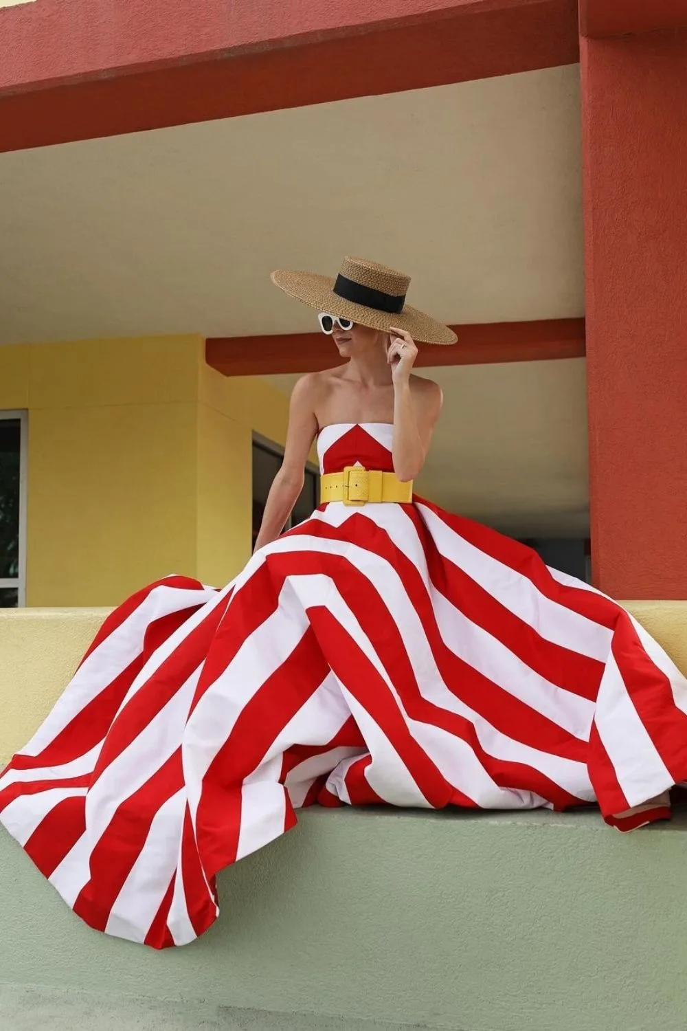 Blair sitting and posing in a red and white stripes dress