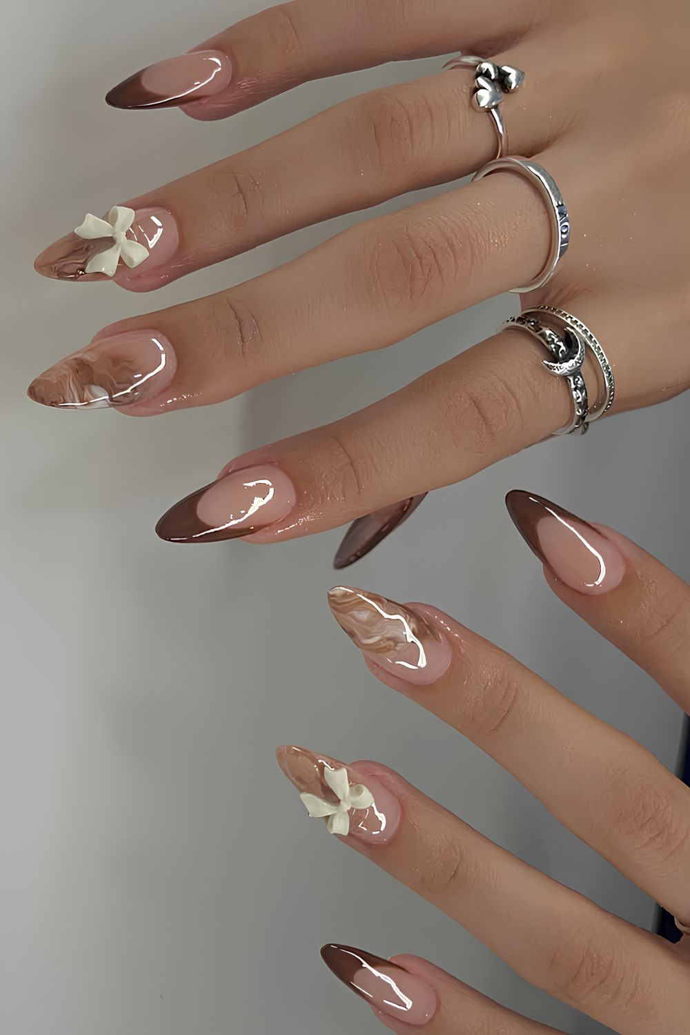 Brown French nails with marble and bow accents