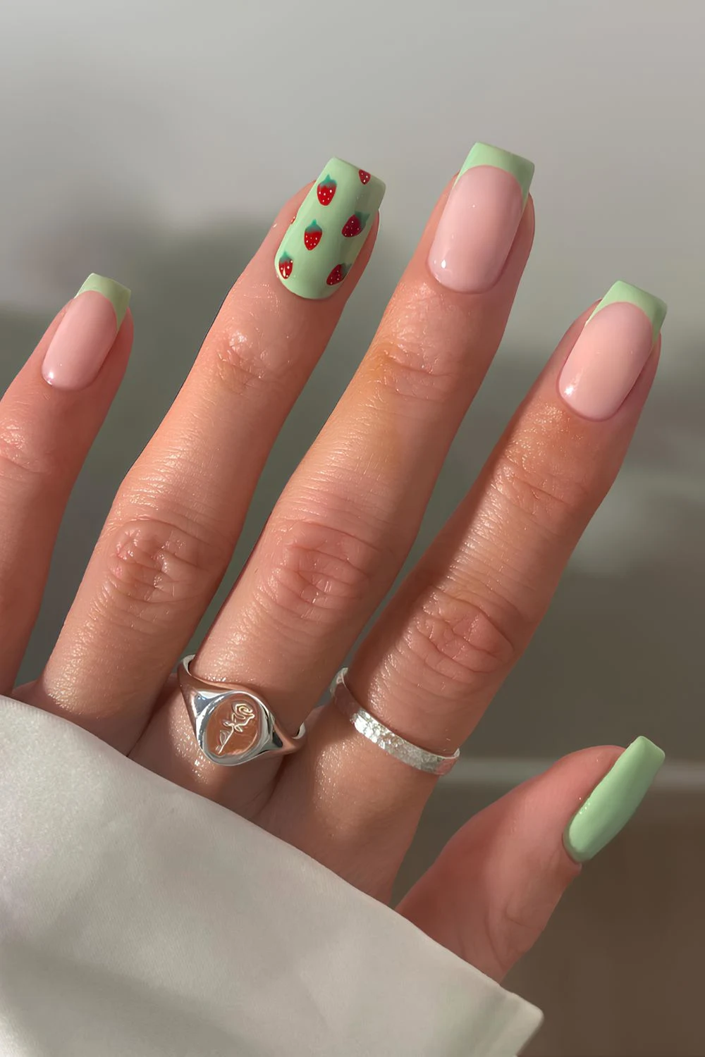 Green manicure with strawberry art