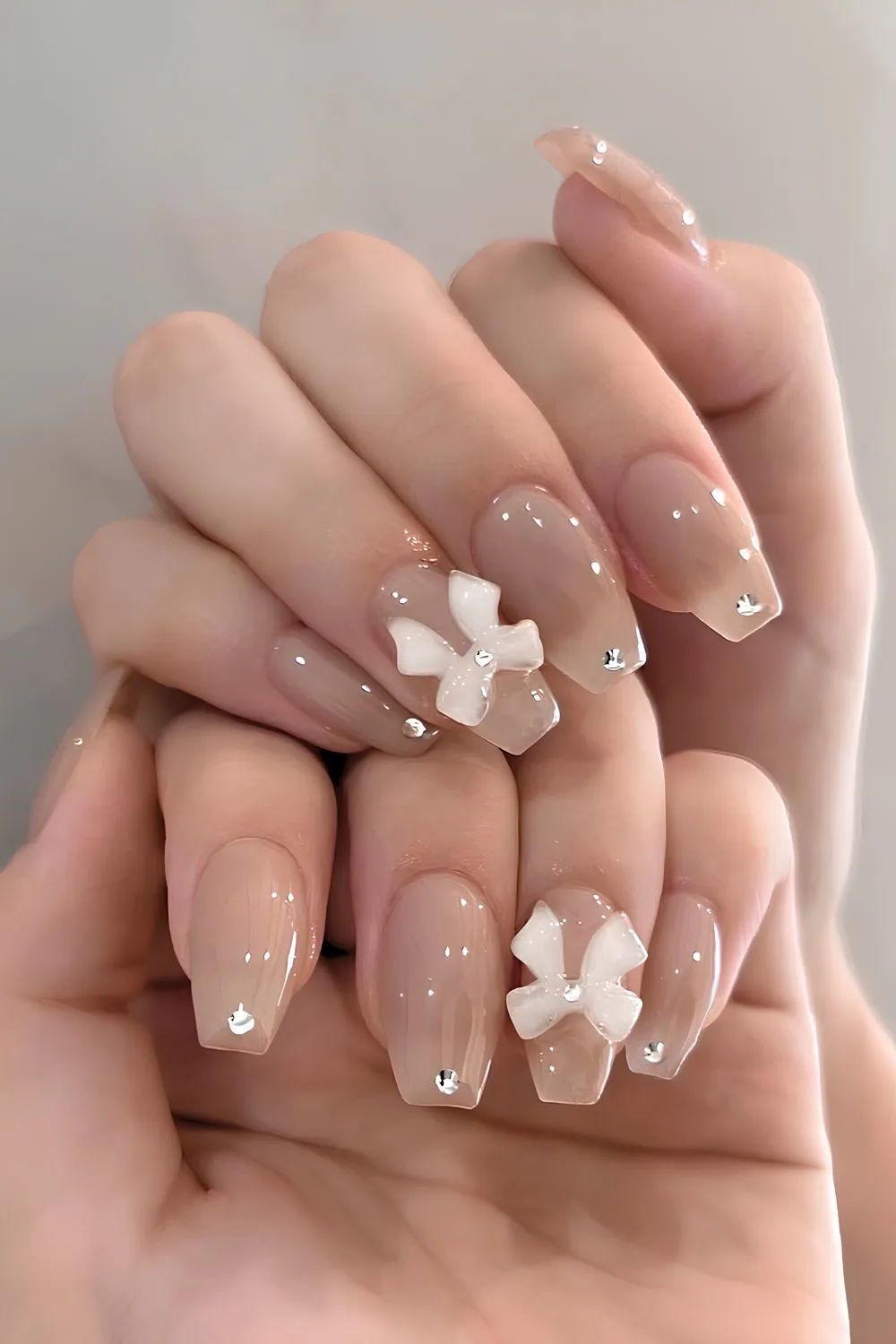 Neutral coquette nails with bows and gems