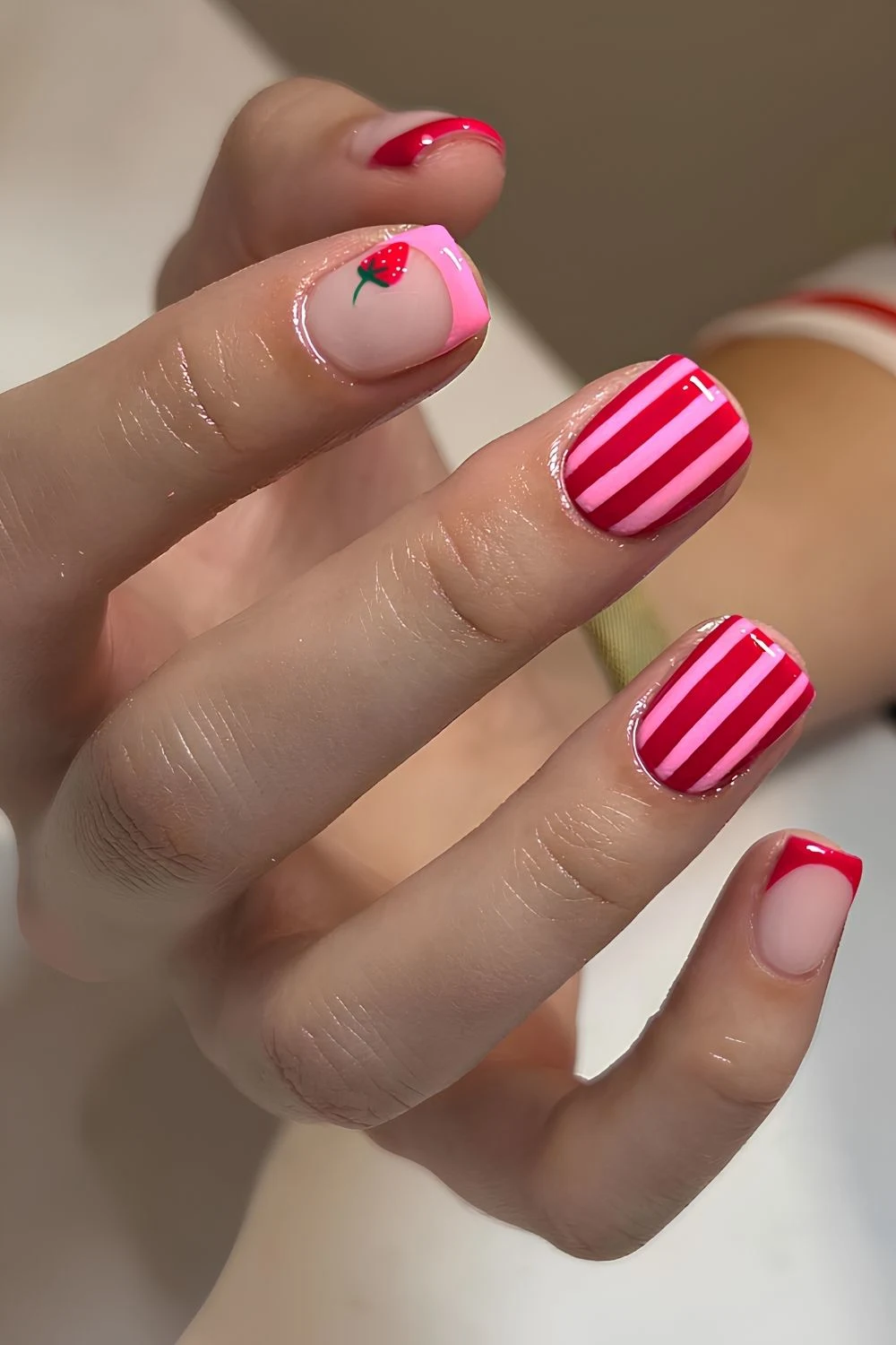 Pink and red nails with stripes and strawberries