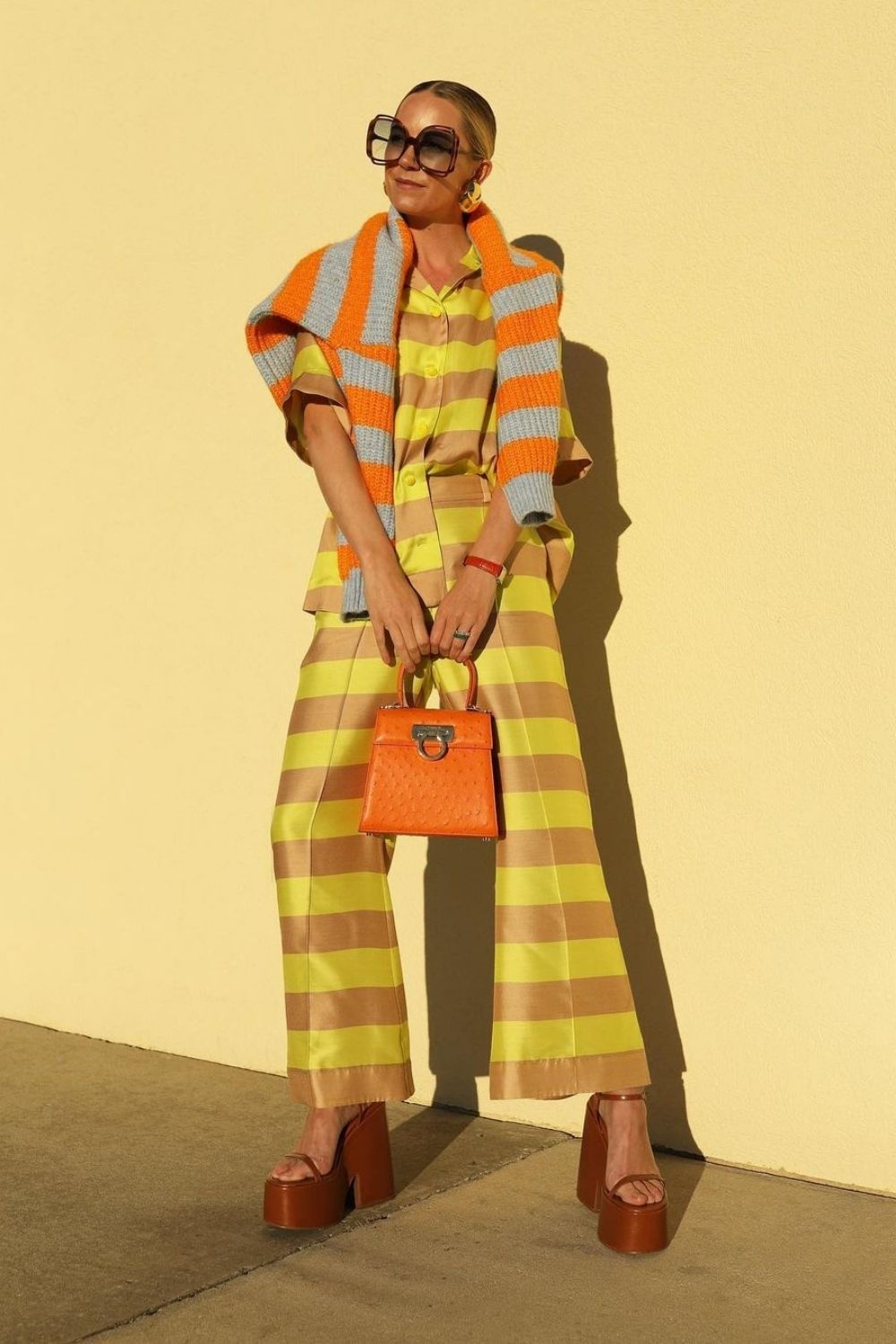 a model posing in a sun wearing yellow stripe suit with orange details