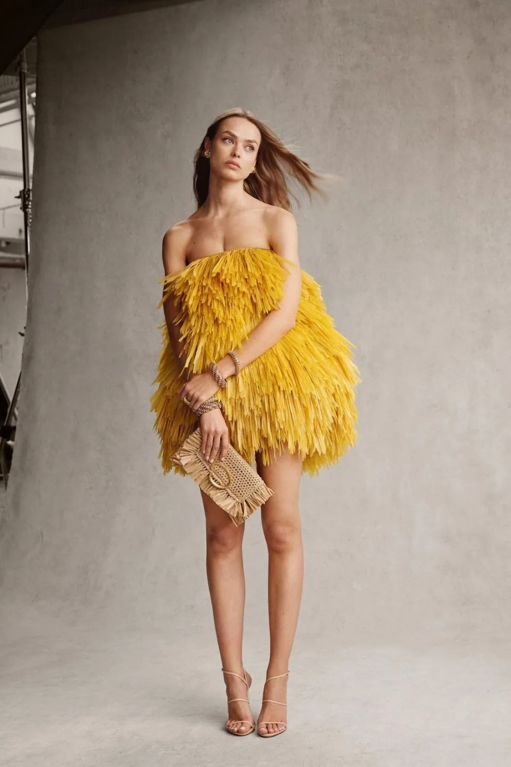 a model posing in yellow fringe dress