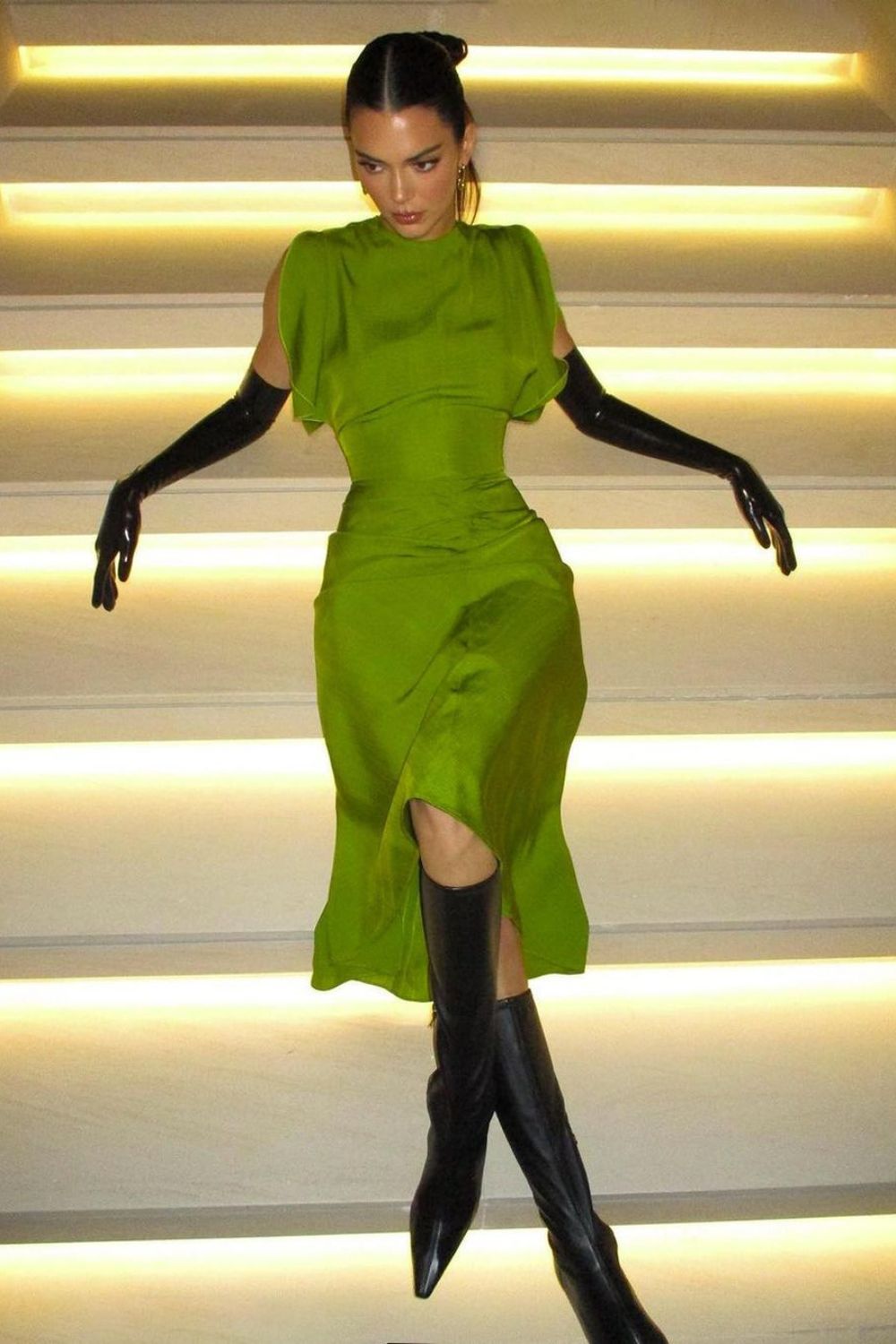 a model posing on the stairs in a green dress