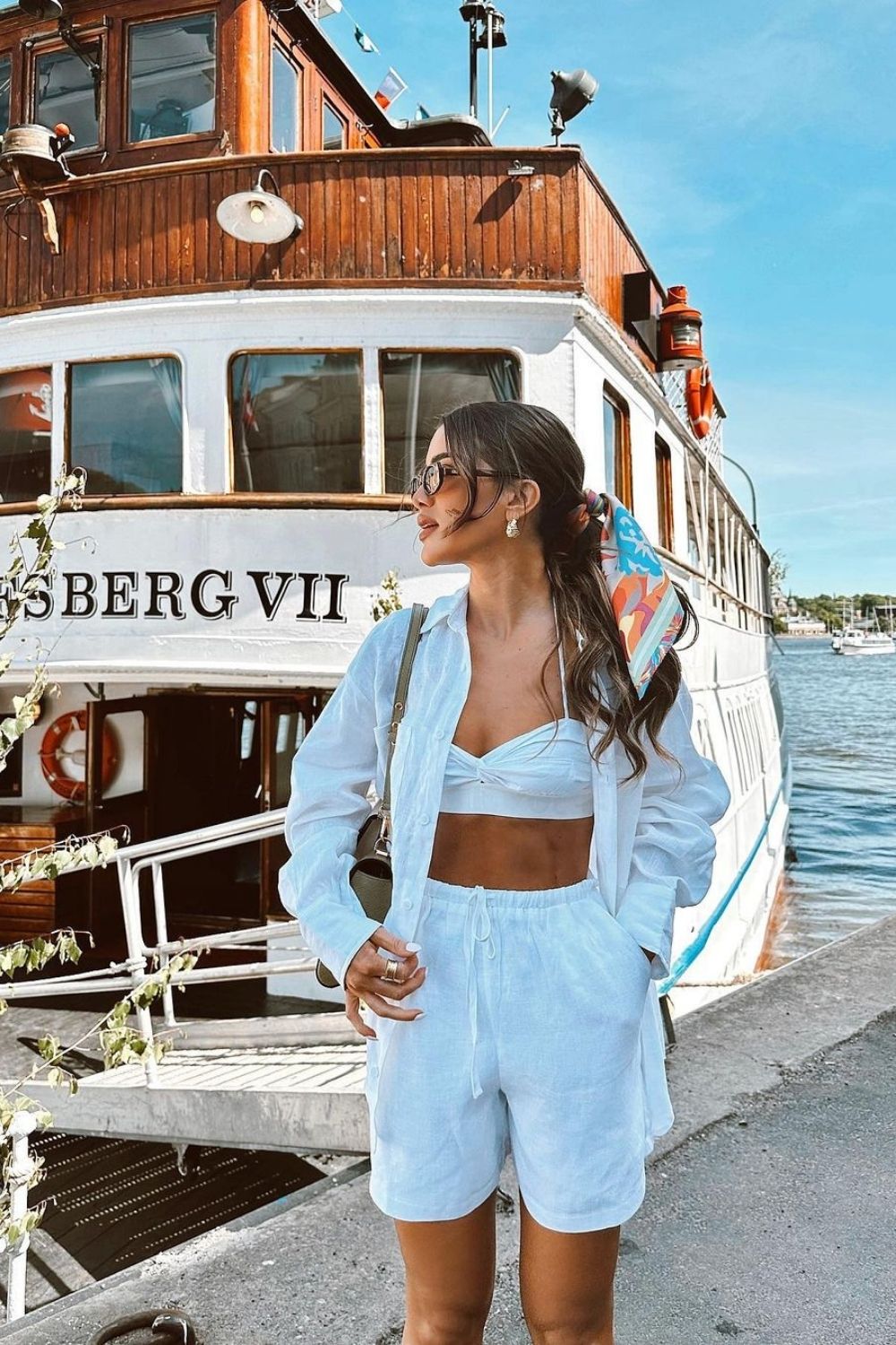 a woman in a white set standing by the boats