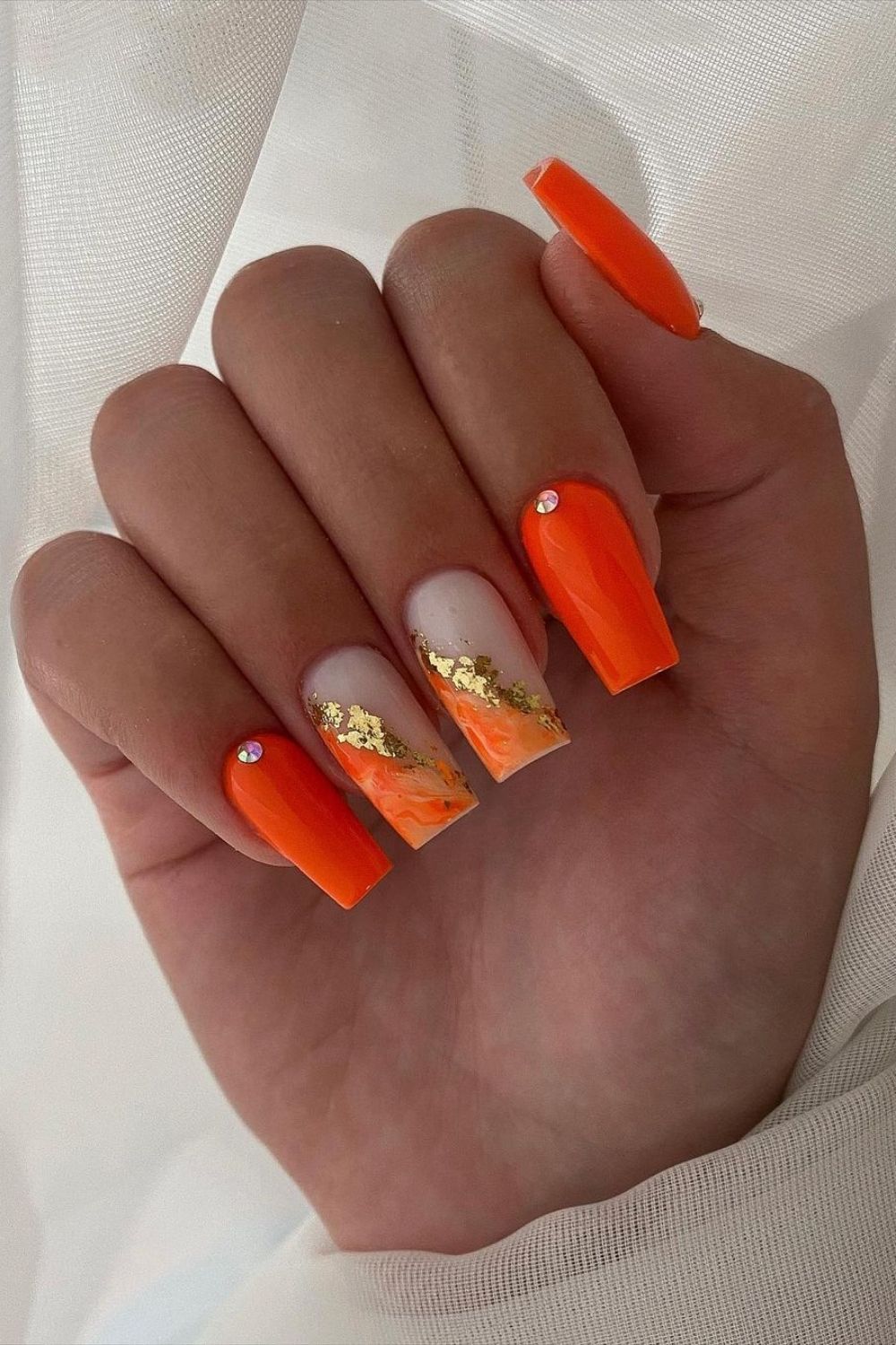 orange neon nails with gold accents