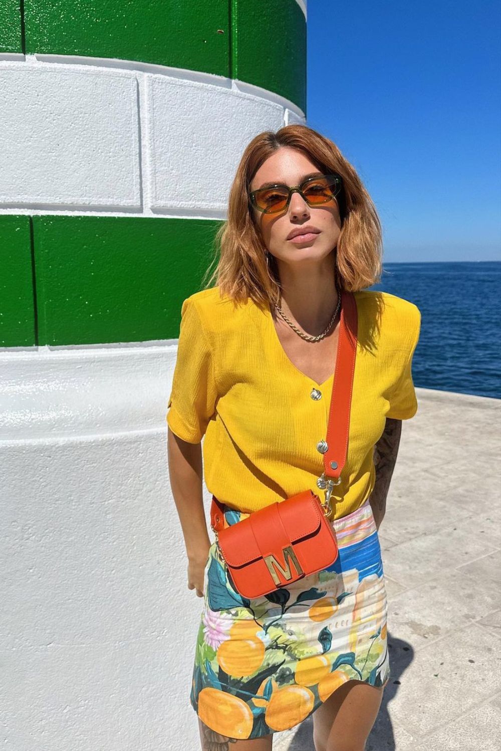 woman posing in a floral skirt and a yellow shirt