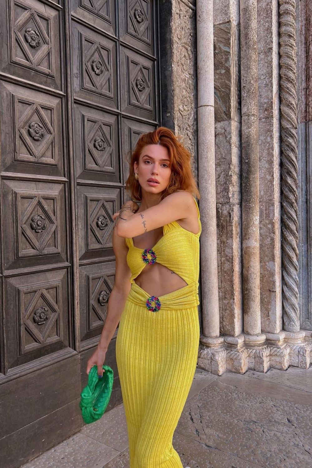 woman posing in a yellow dress and a green bag