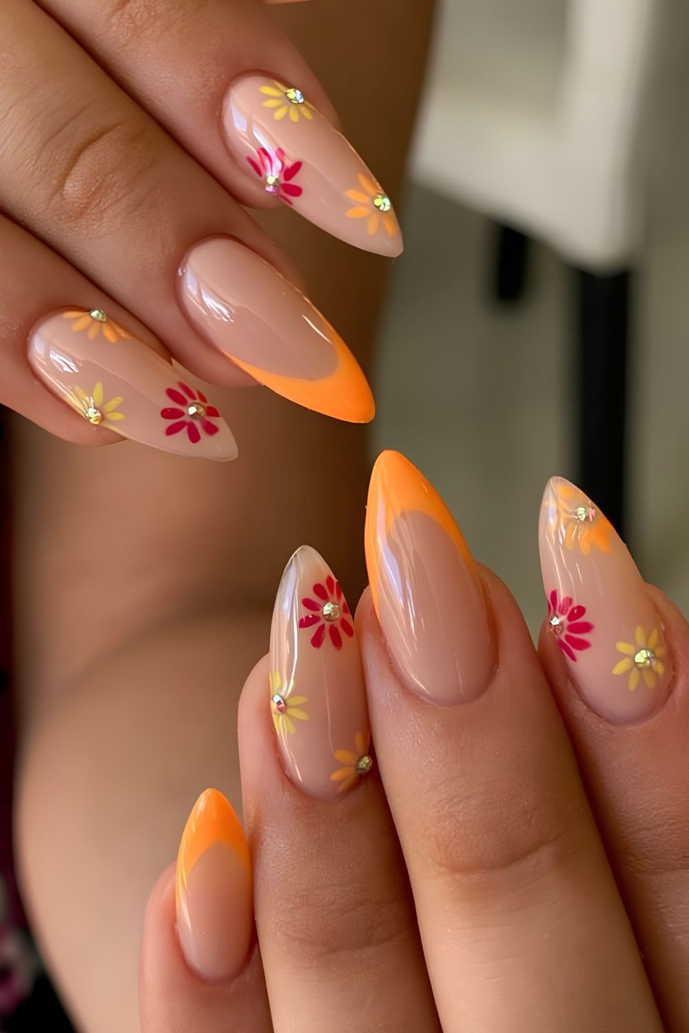 Neutral nails with orange tips and flower with gem accents
