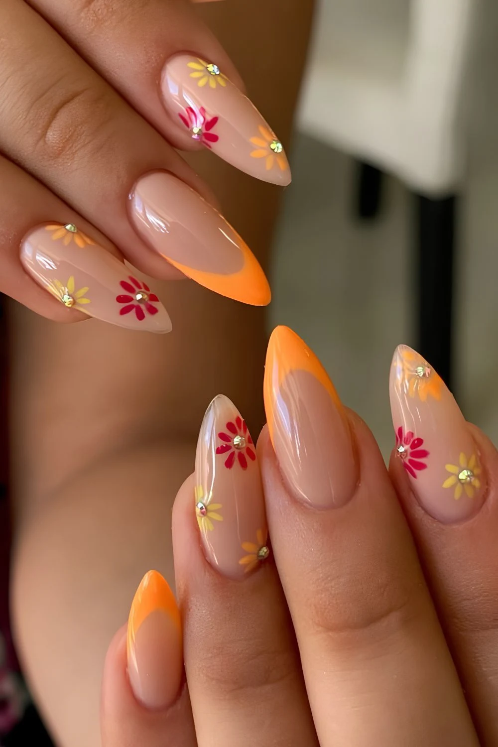 Neutral nails with orange tips and flower with gem accents