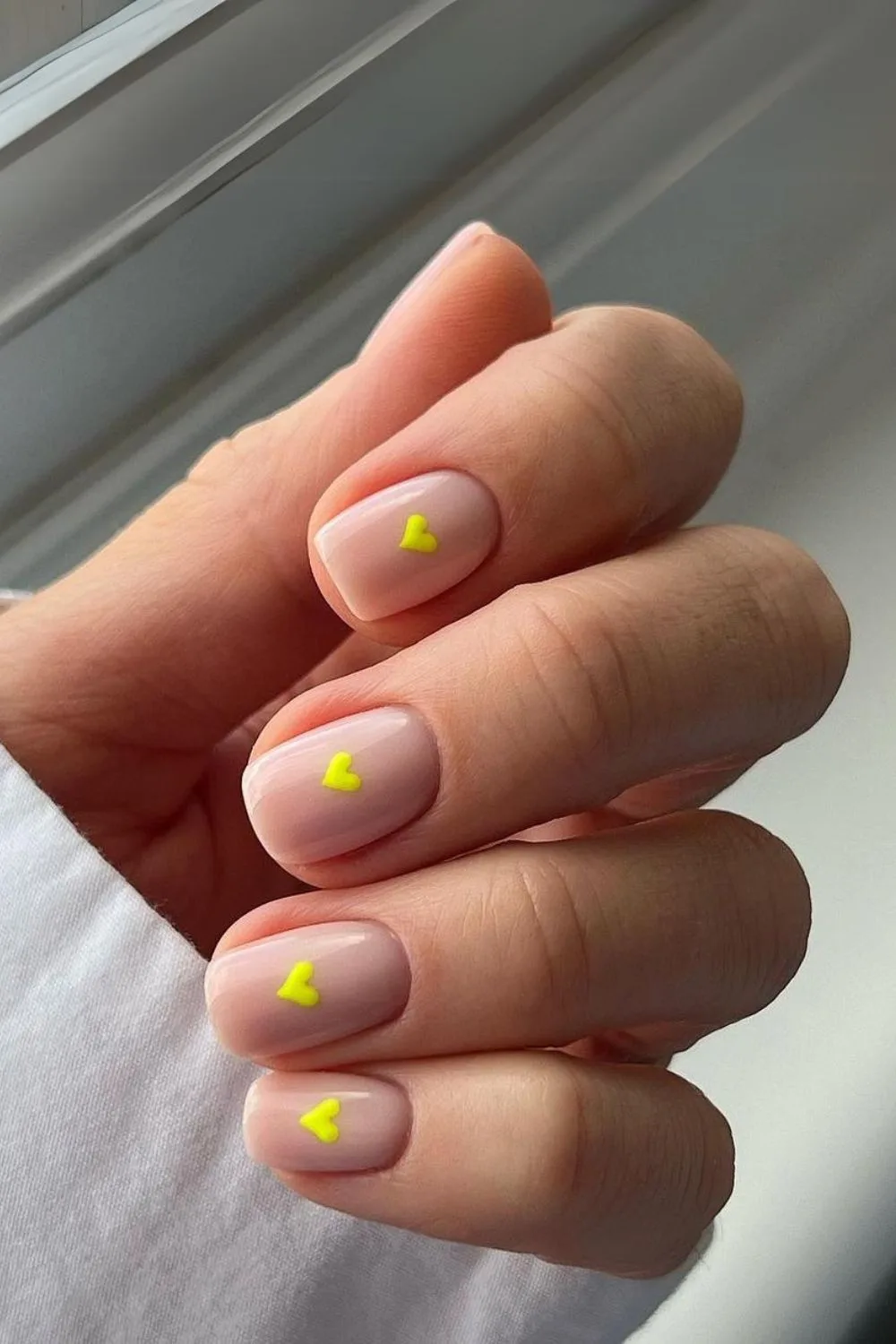 Nude nails with neon yellow hearts