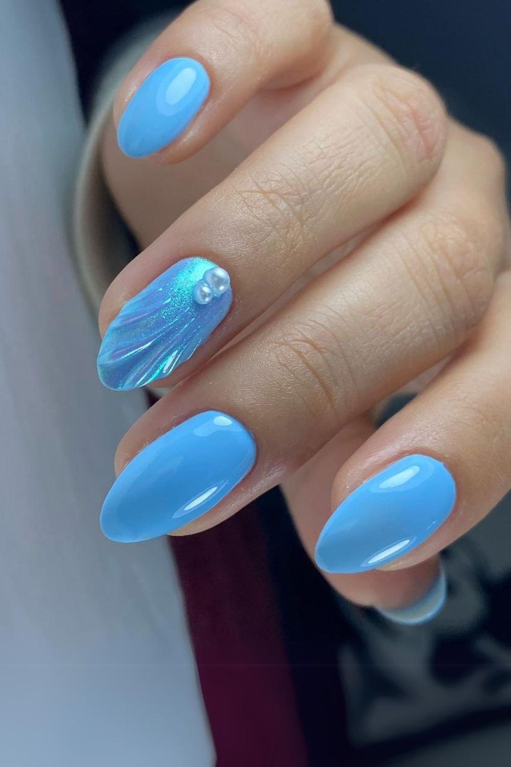 Ocean blue nails with pearl-embellished seashell