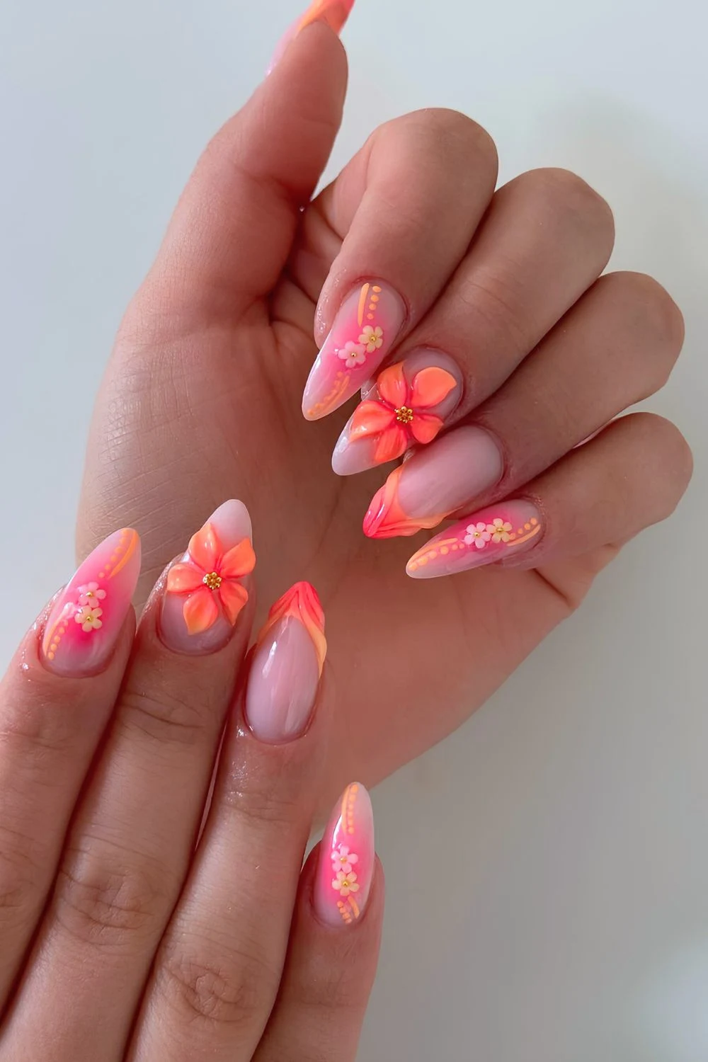 Orange and pink nails with sculpted flower accents