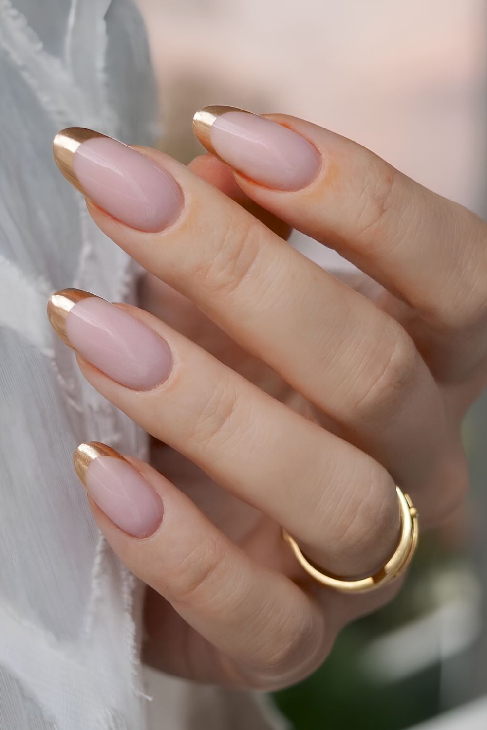 Gold French tip nails on milky pink base