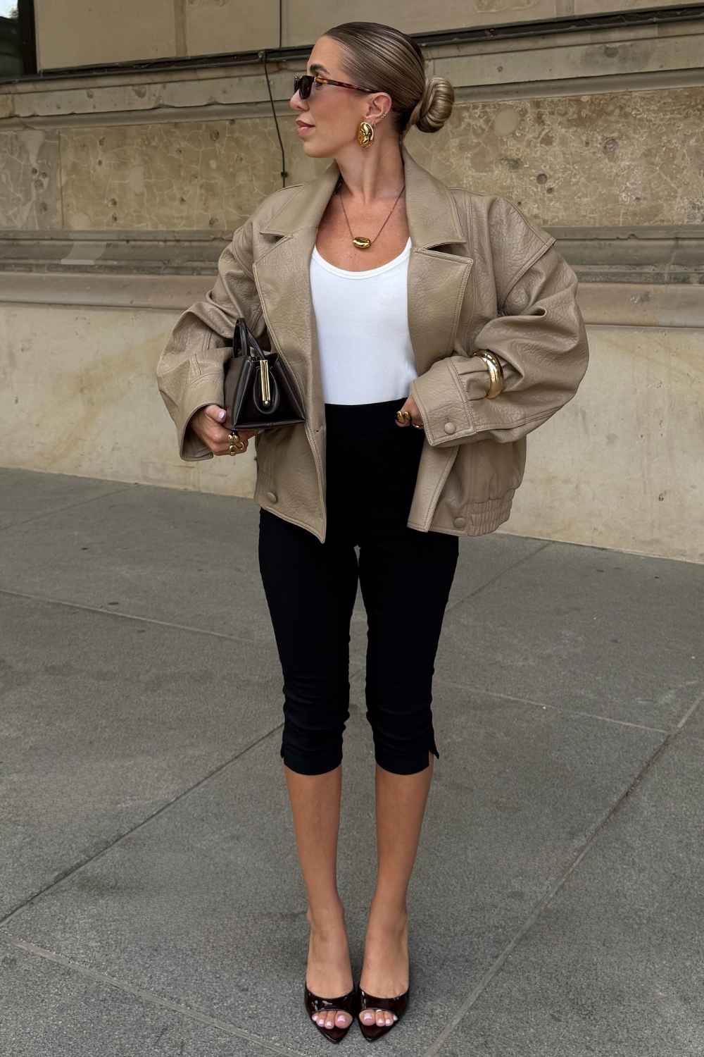 beige leather jacket with white tank and black capri leggings
