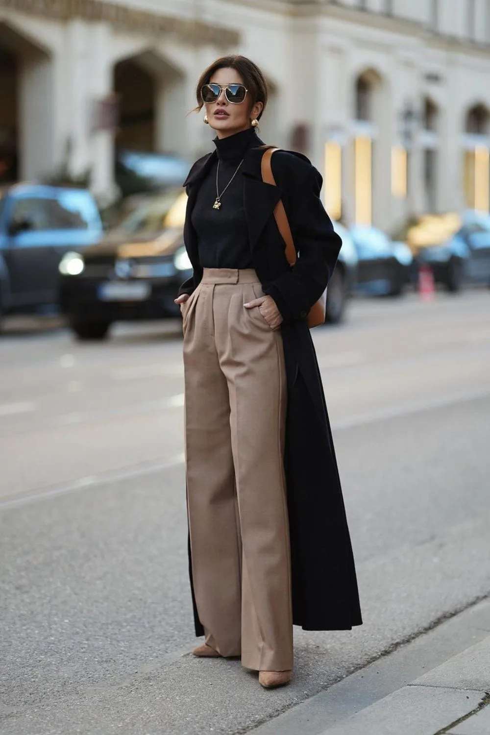 Black coat with turtleneck and high-waisted tan trousers