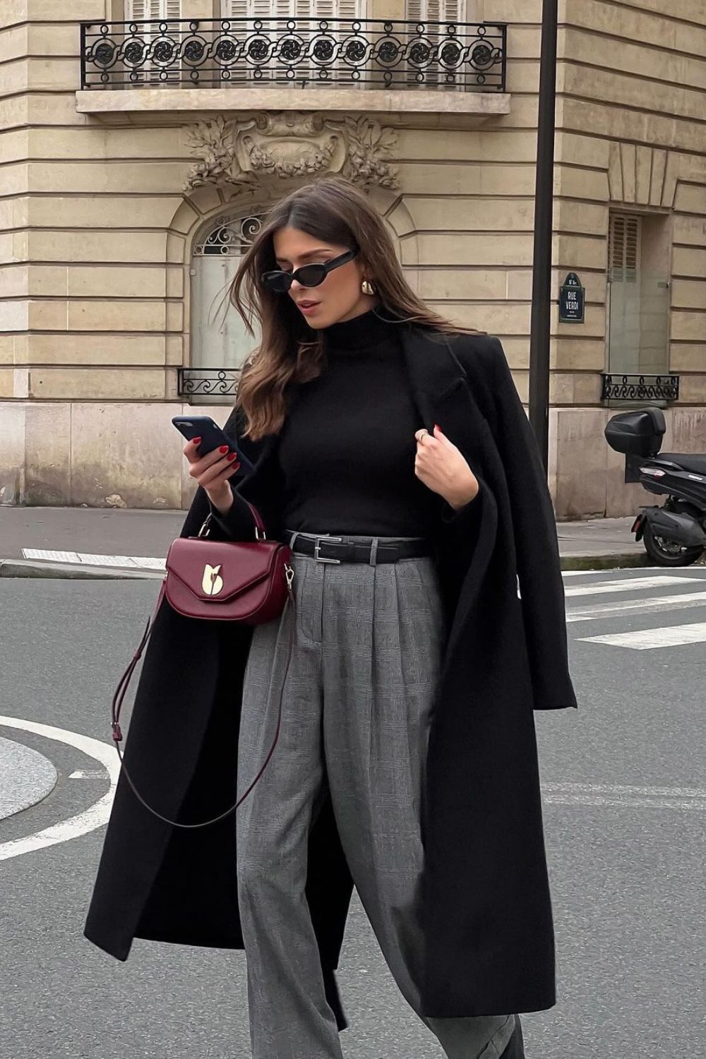 Black coat with turtleneck, wide-leg trousers and maroon bag