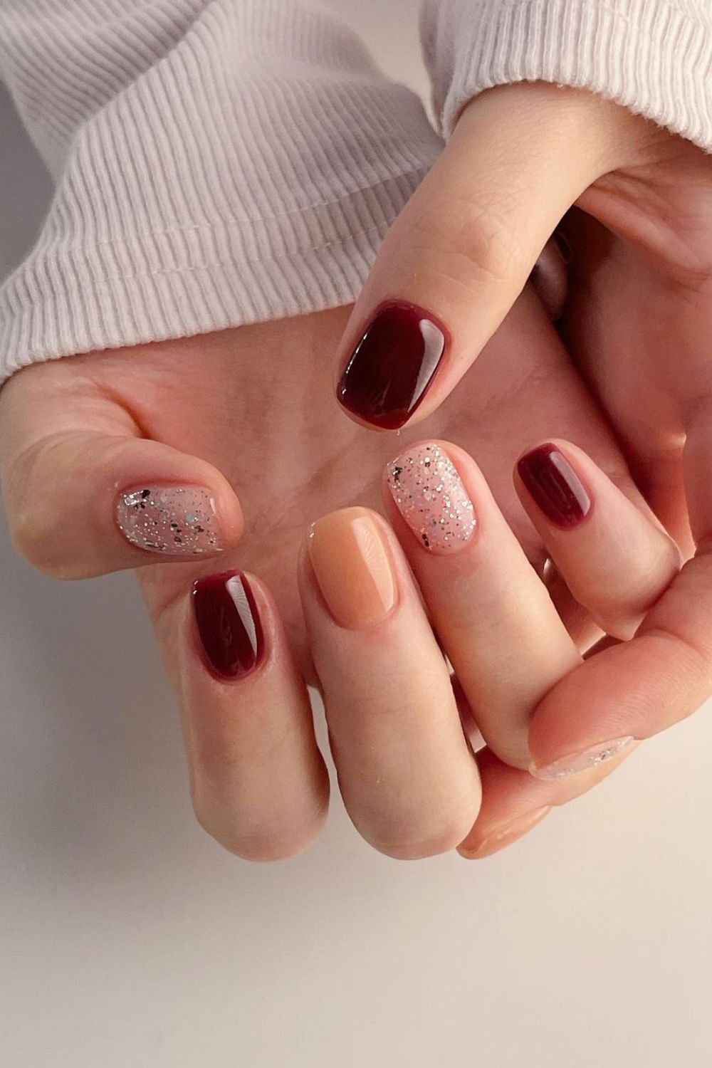 Burgundy and orange nails with glitter accents