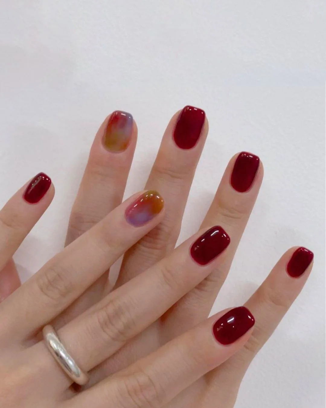 Burgundy manicure with marble accent nails