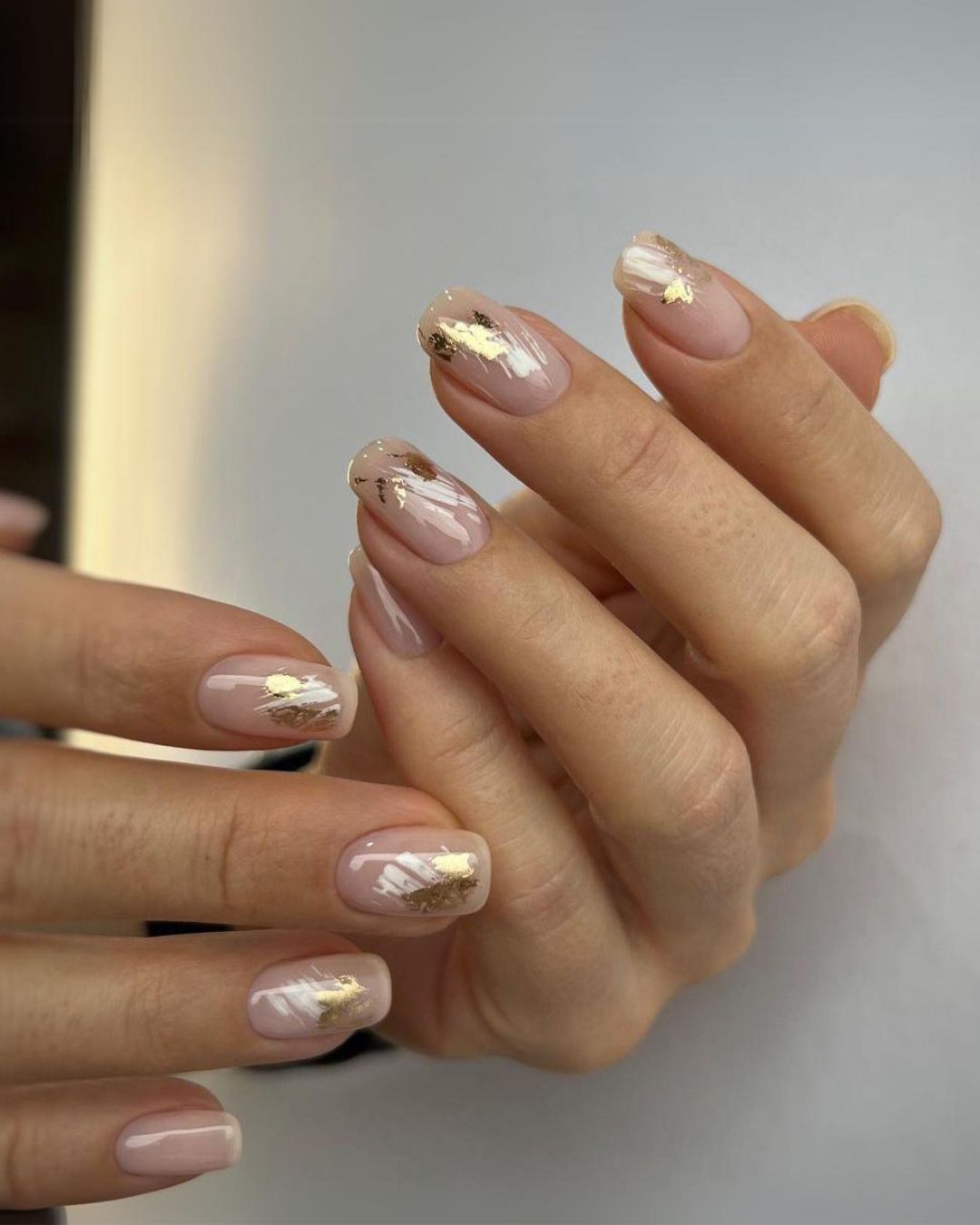 Nude nails with white brushstrokes and gold foil