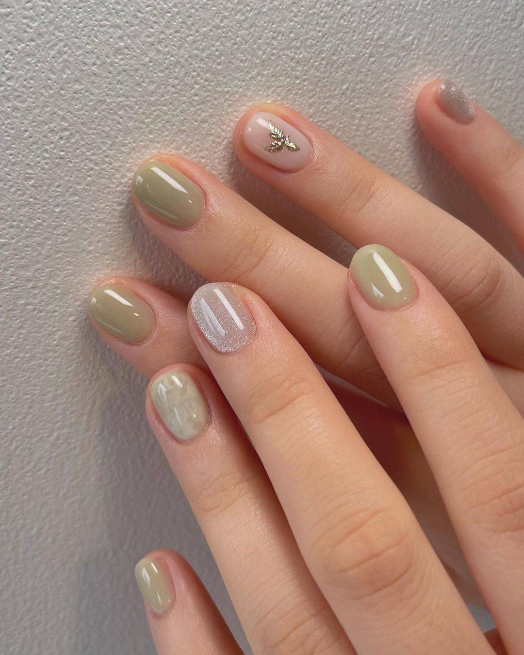 Sage green nails with marble and gold charms