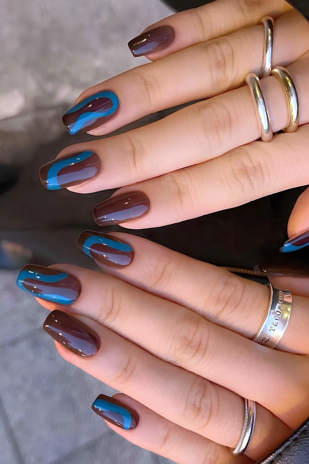 Brown nails with blue swirl art