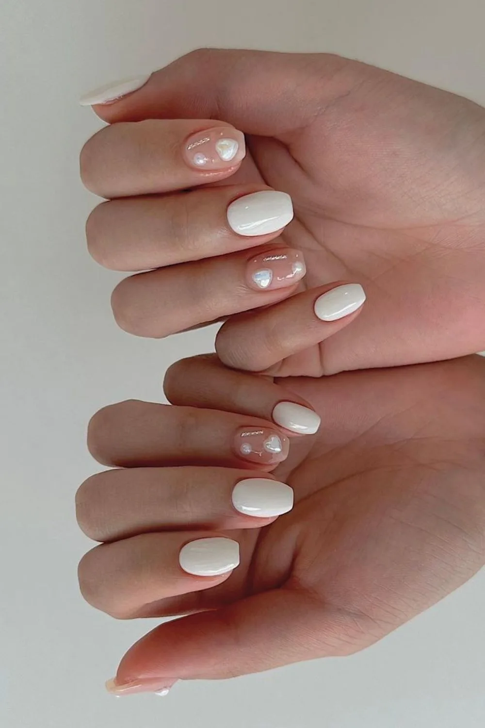 Creamy white nails with 3d heart-shaped pearls