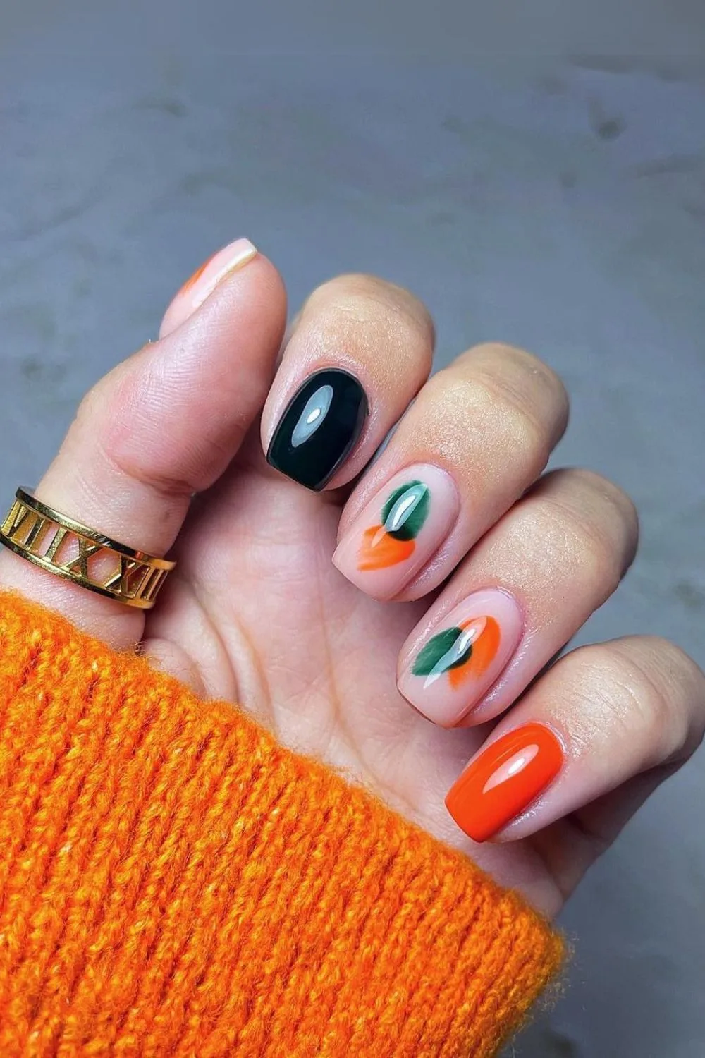 Dark green and orange nails with abstract accent design