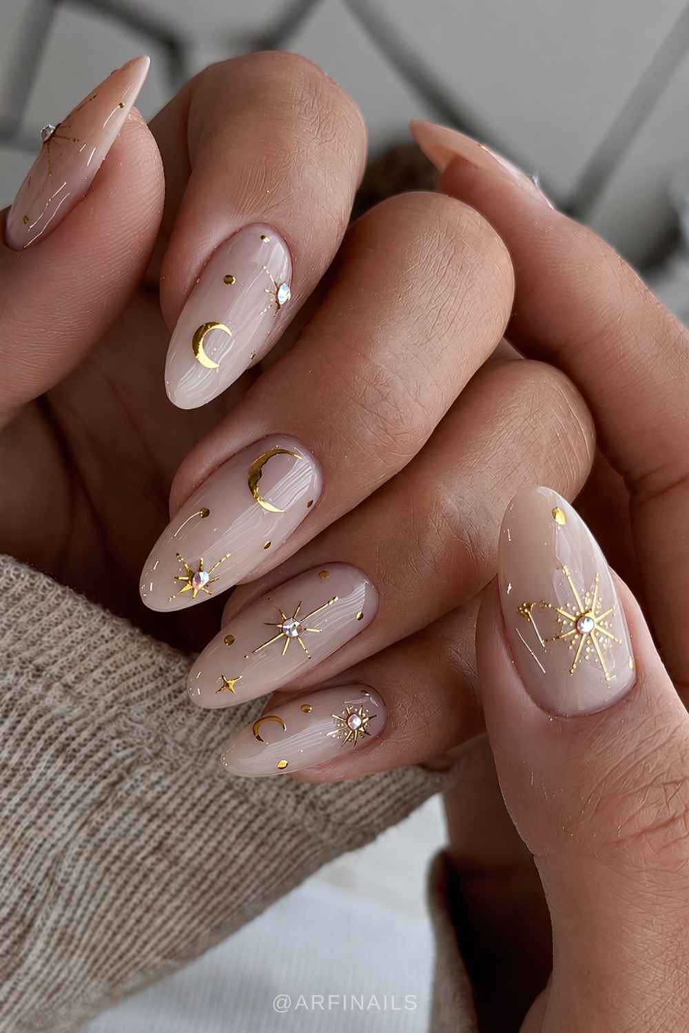 Glossy neutral nails with gold celestial details