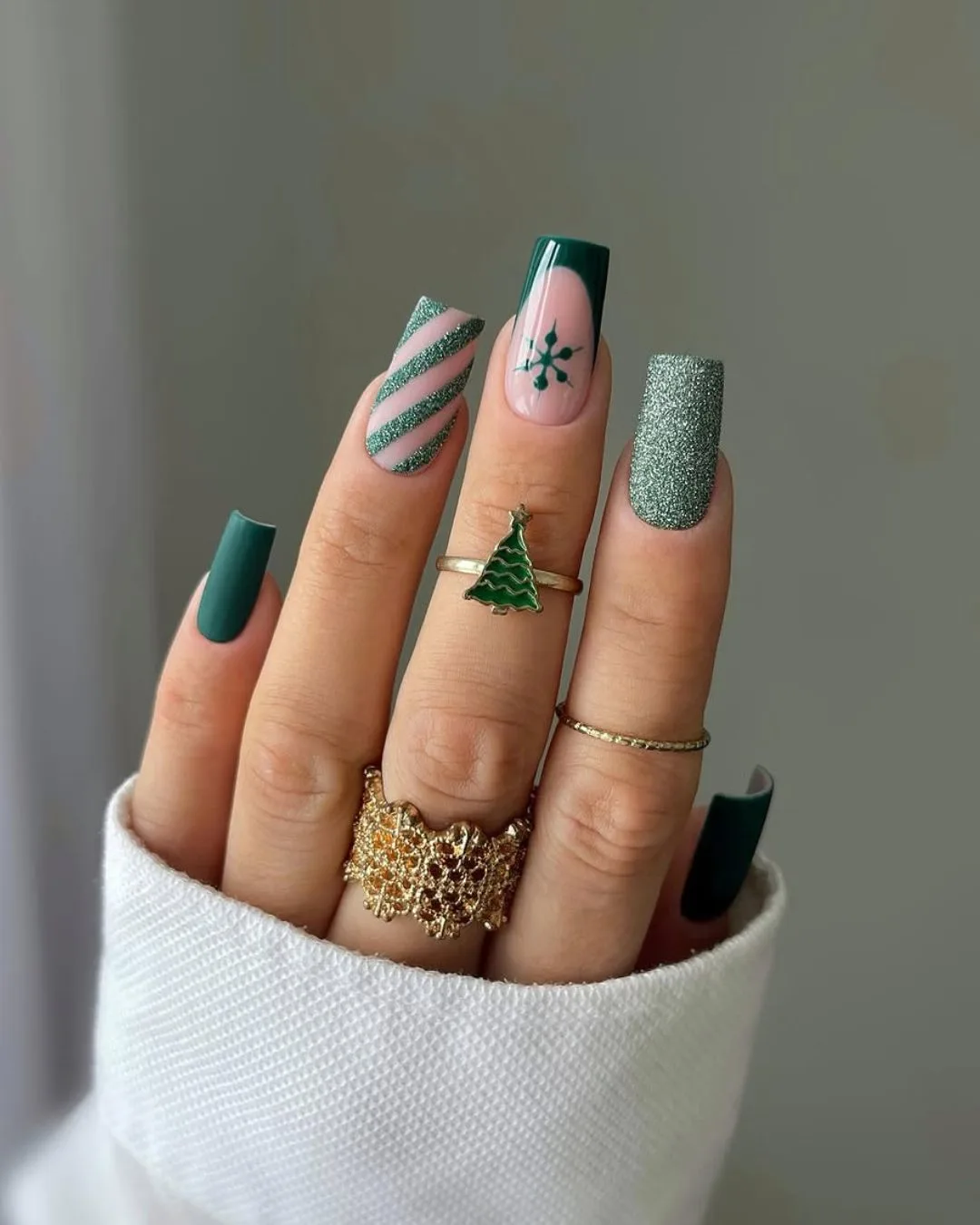 Green manicure with glitter accents a green snowflake design and candy cane-inspired stripes