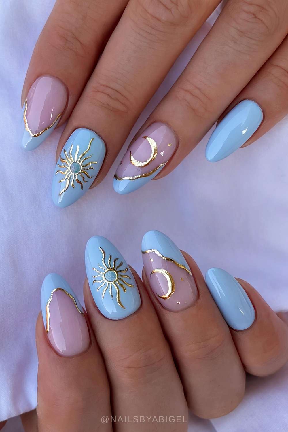 Light blue nails with gold sun and moon art