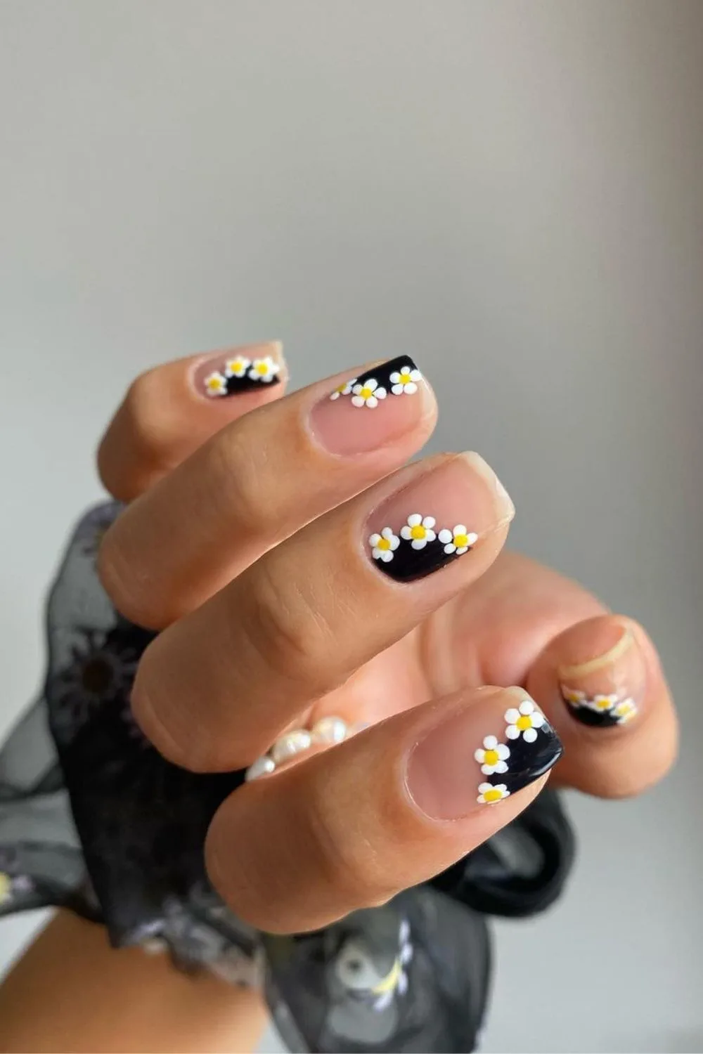 Nude nails with black side-tips and daisy accents