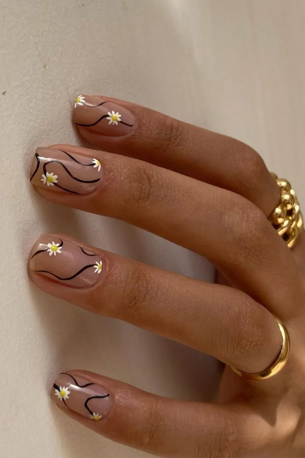 Nude nails with daisies and black swirls