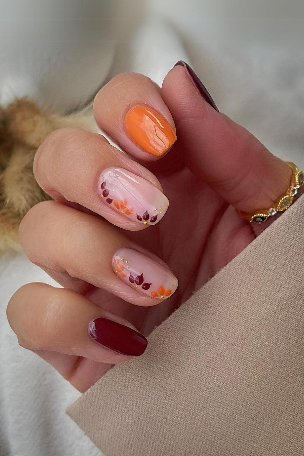 Orange and maroon nails with leaf design