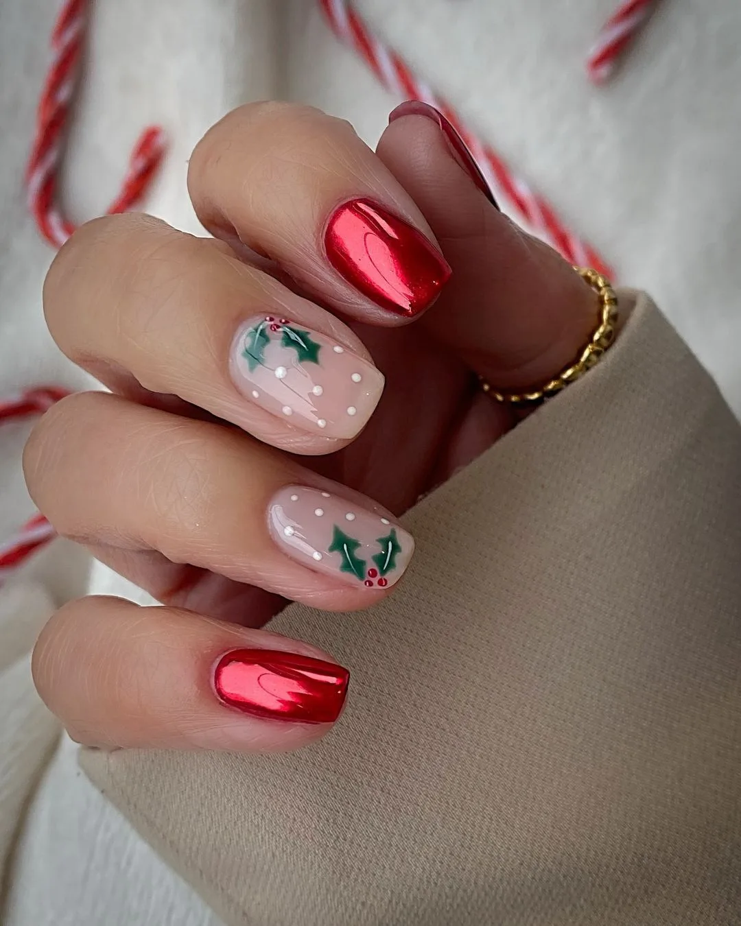 Red chrome nails and nude nails with white snow like dots and holly accents