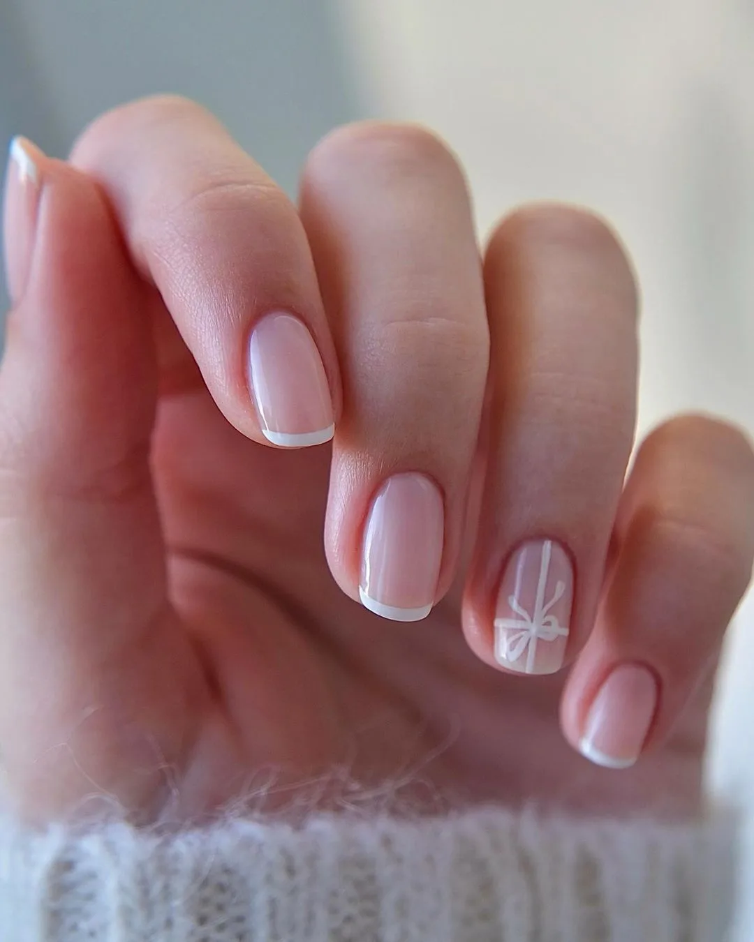 Short French tip manicure with a cute white ribbon