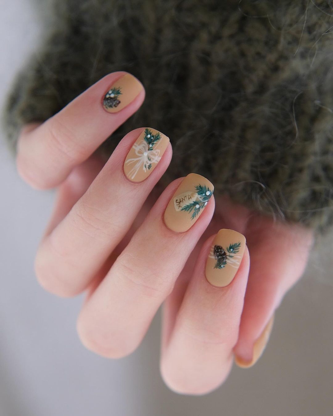 Short matte tan nails with pinecones and Santa detail