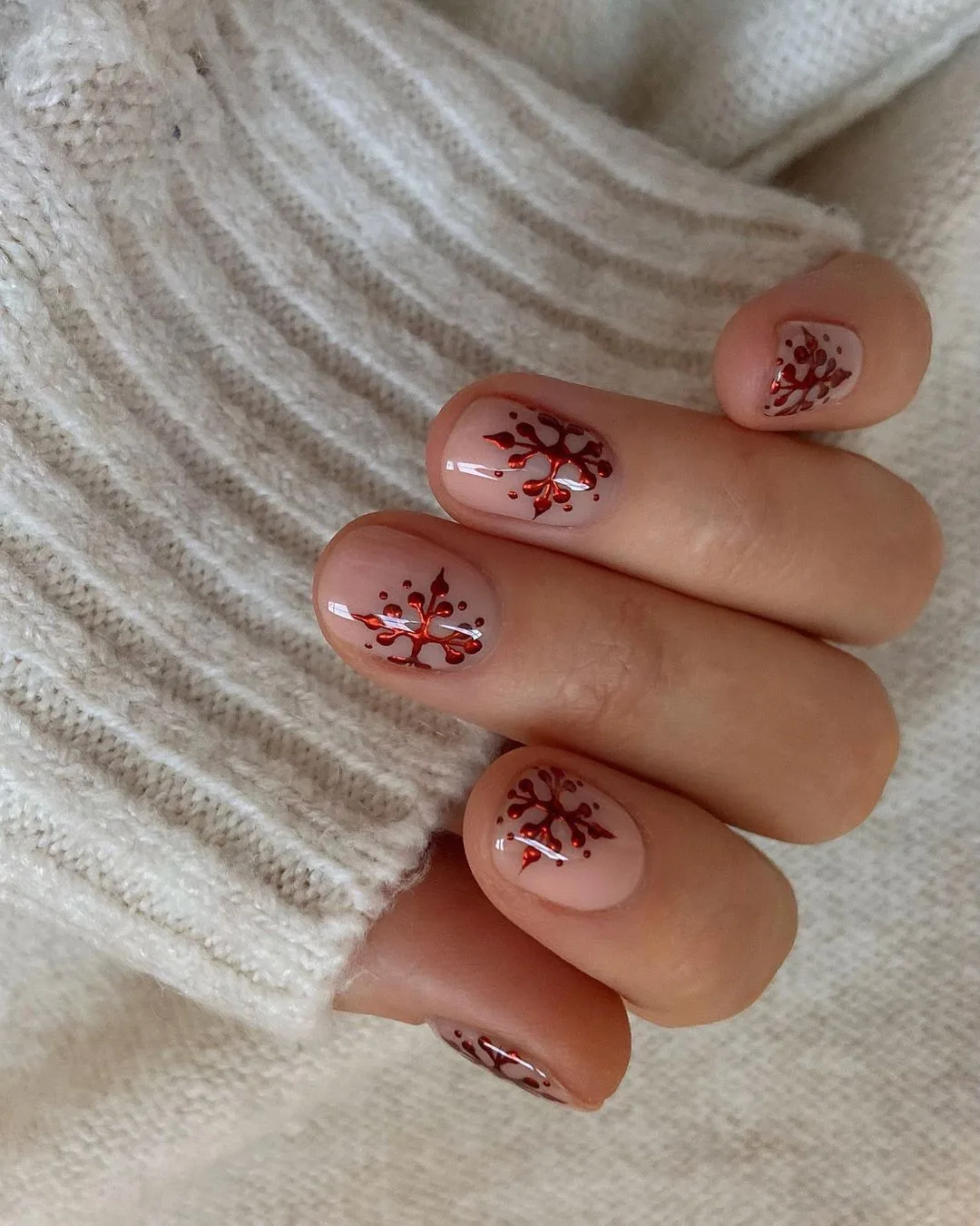 Short nude nails with red metallic snowflakes