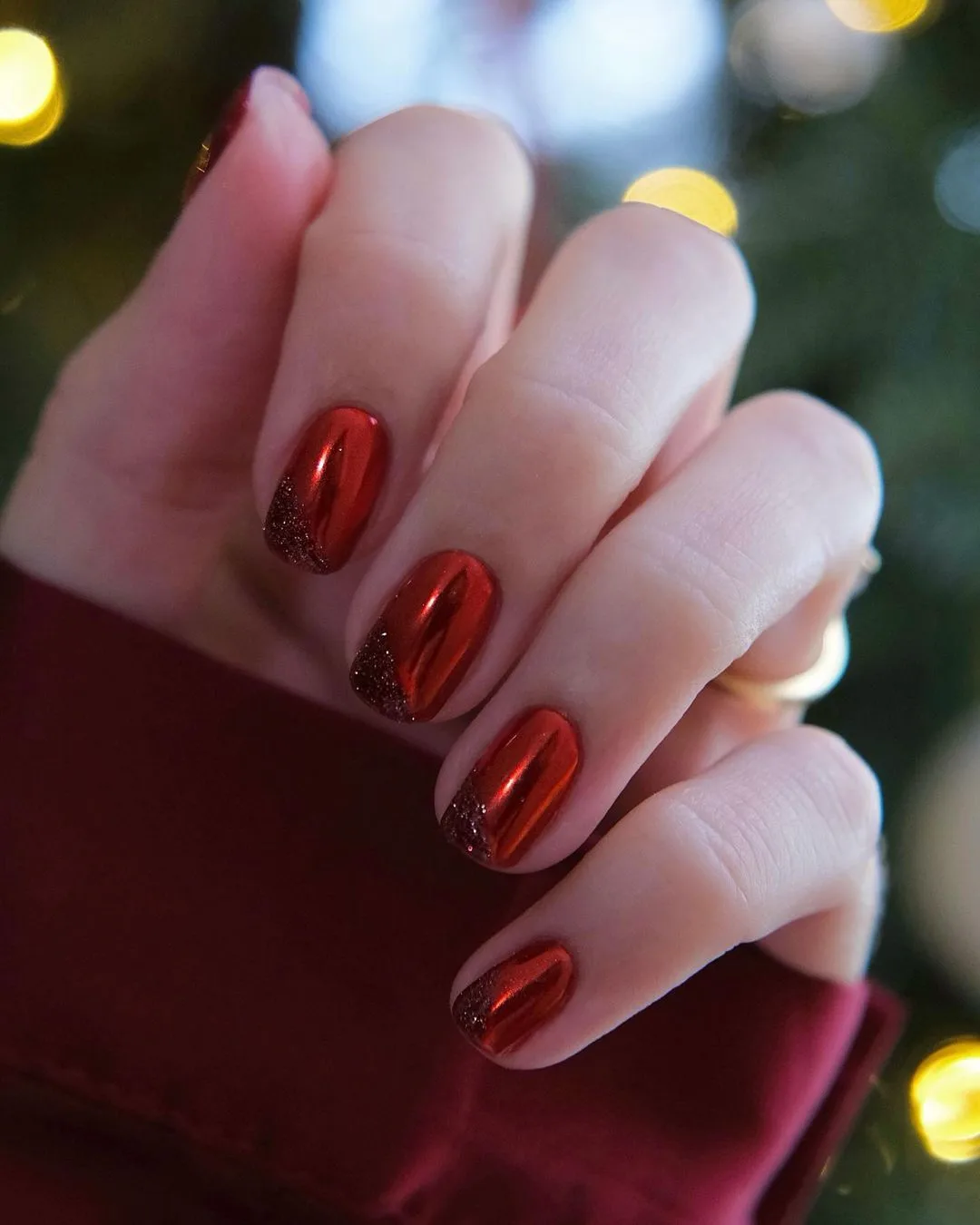 Short red chrome nails with black glitter-dipped tips