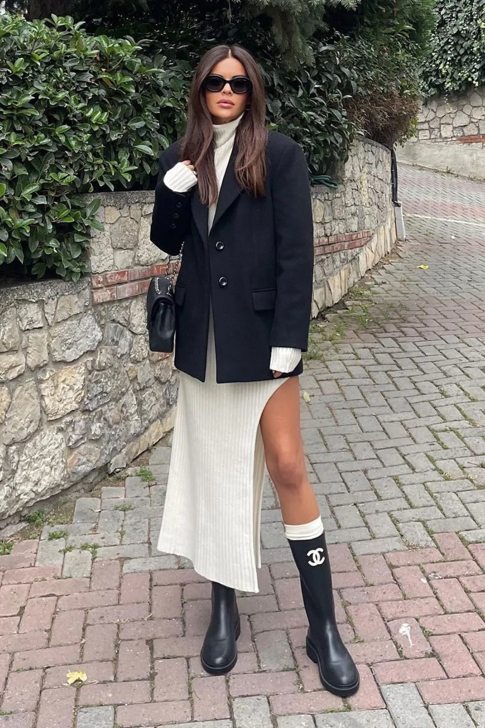 black blazer over white ripped dress with high knee black boots.