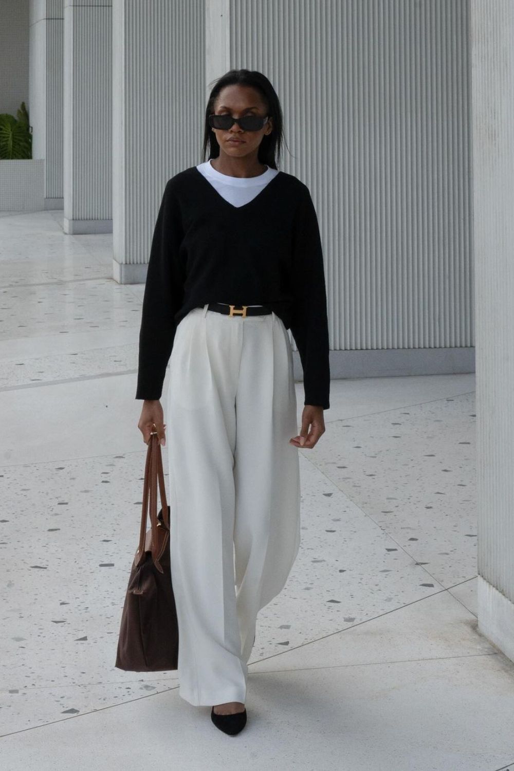 black v-neck sweater and white t-shirt paired with white wide leg pants