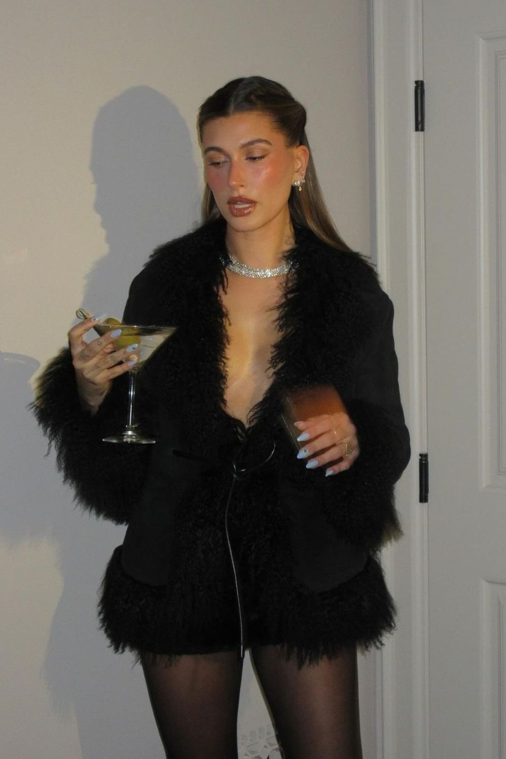 Famous trendsetter Hailey Bieber posing with martini in black fur coat for her birthday