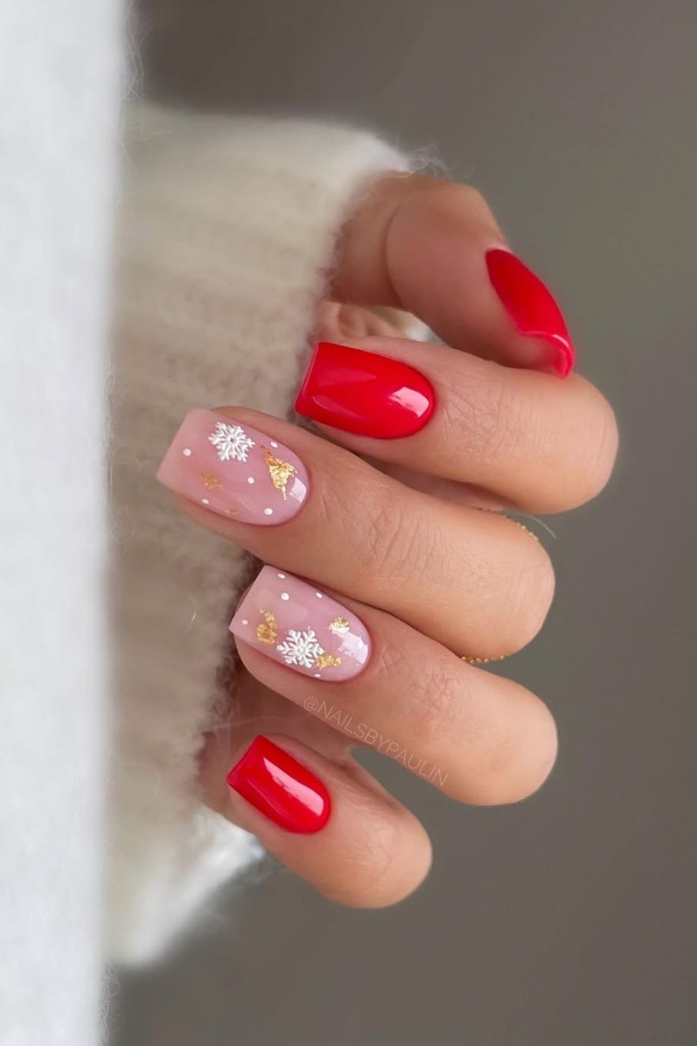 Red and pink nails with white snowflakes and gold flecks