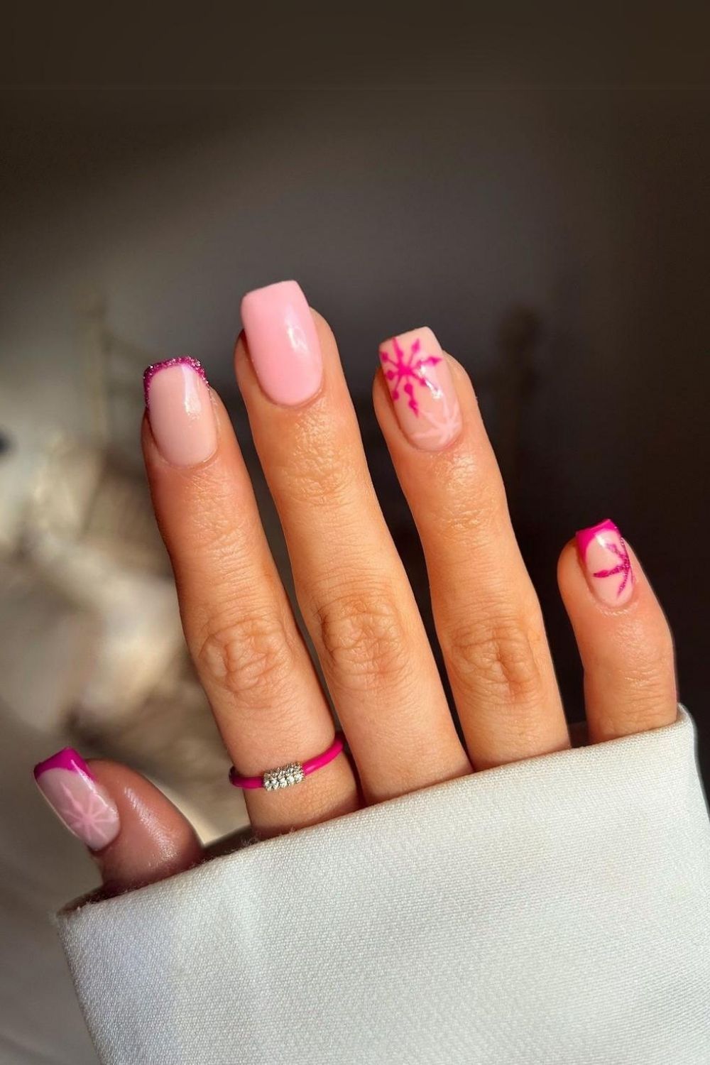 Light pink base with vibrat pink snowflakes and French tips