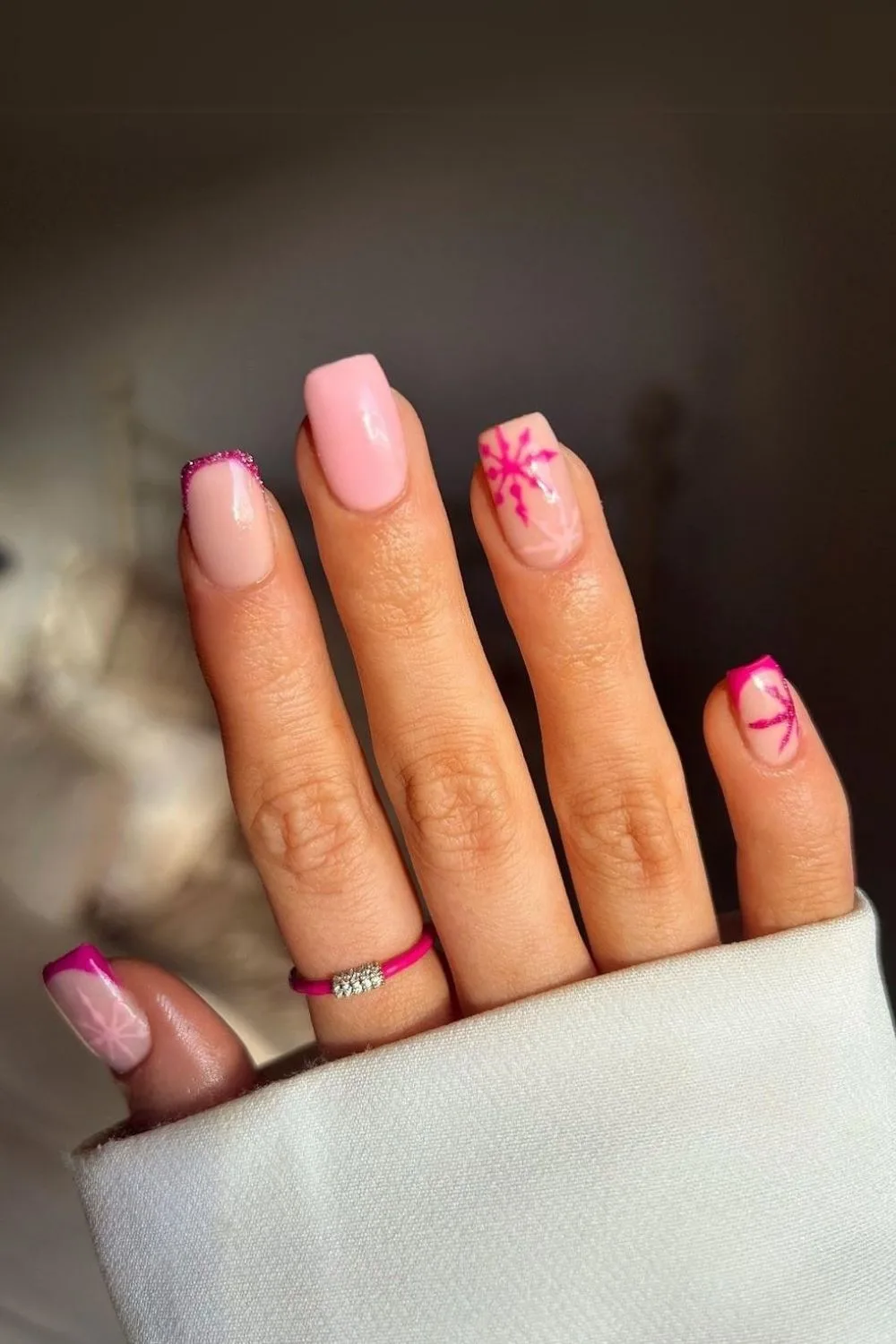 Light pink base with vibrat pink snowflakes and French tips