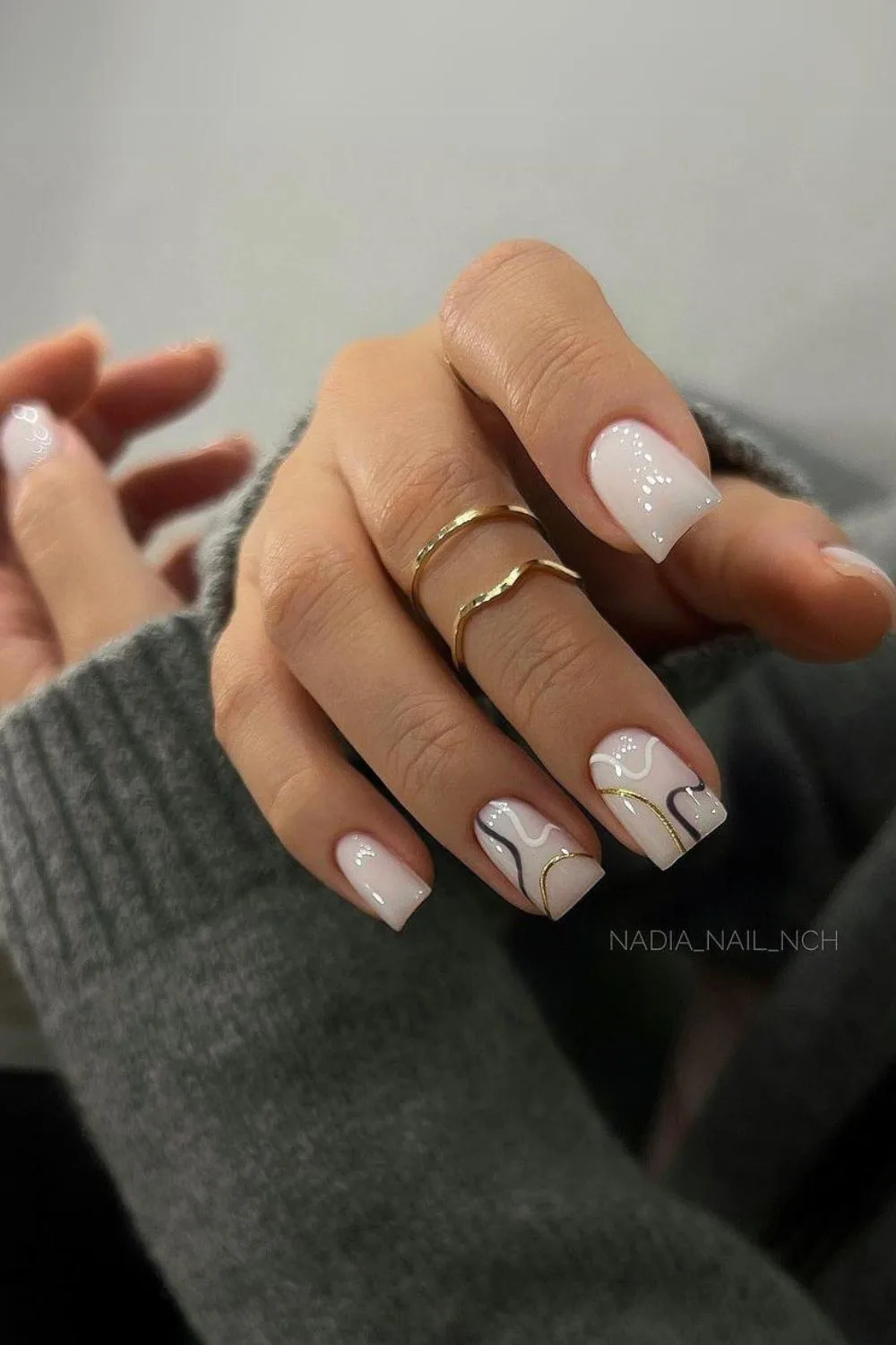 White nails with black and gold swirls